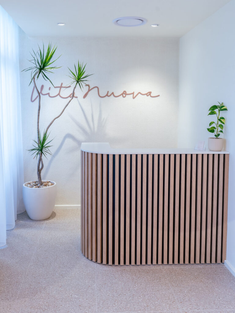 Custom timber panelling, neutral colour palette and welcoming reception area for this wellness & beauty fit out for Vita Nuova