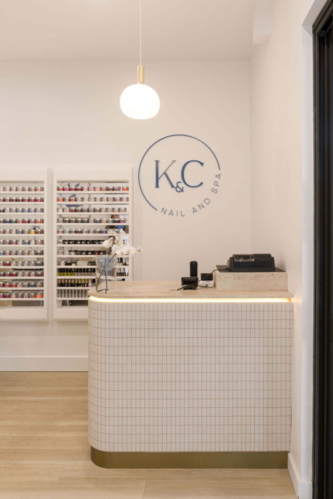 Featured wall pendant lights, square tile curved reception desk and neutral colour palette for this wellness & beauty fit out for K&C Nails, Total Fitouts Sunny Coast South